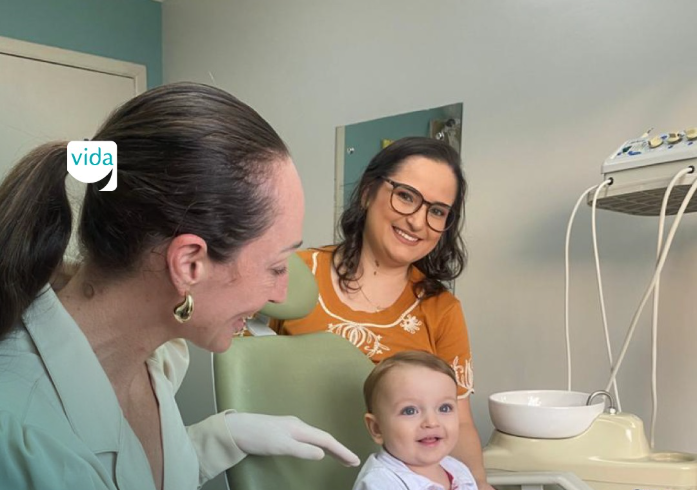 Dentista atendendo bebê no colo da mãe